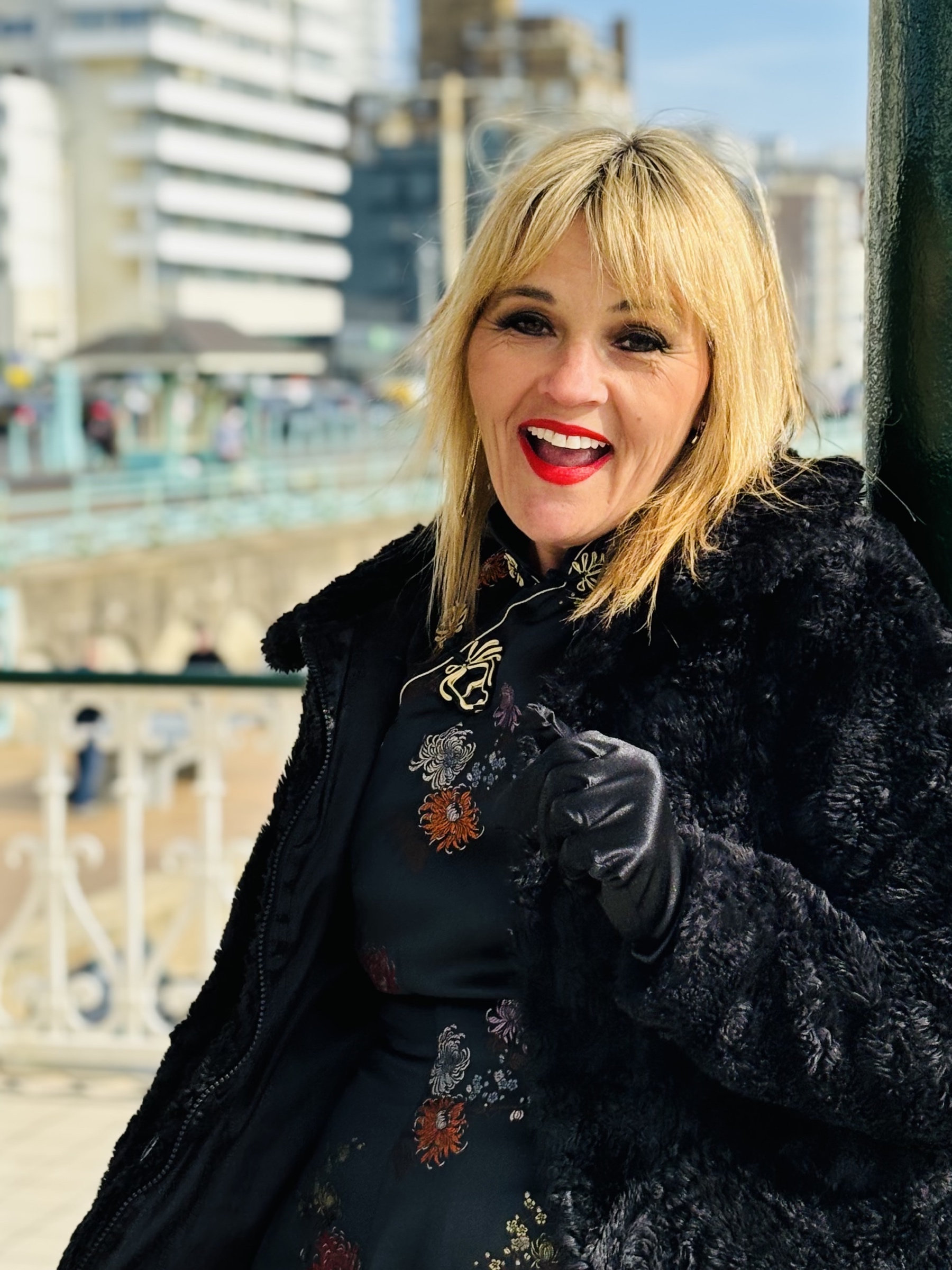Colour portrait of Phillipa A. smiling on Brighton seafront.